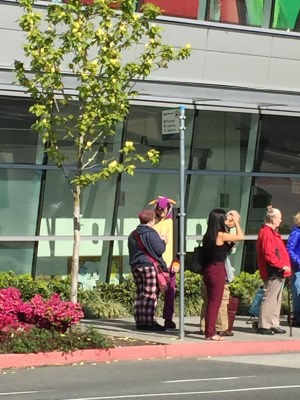 Guy at bus stop wearing a purple dinosaur outfit
